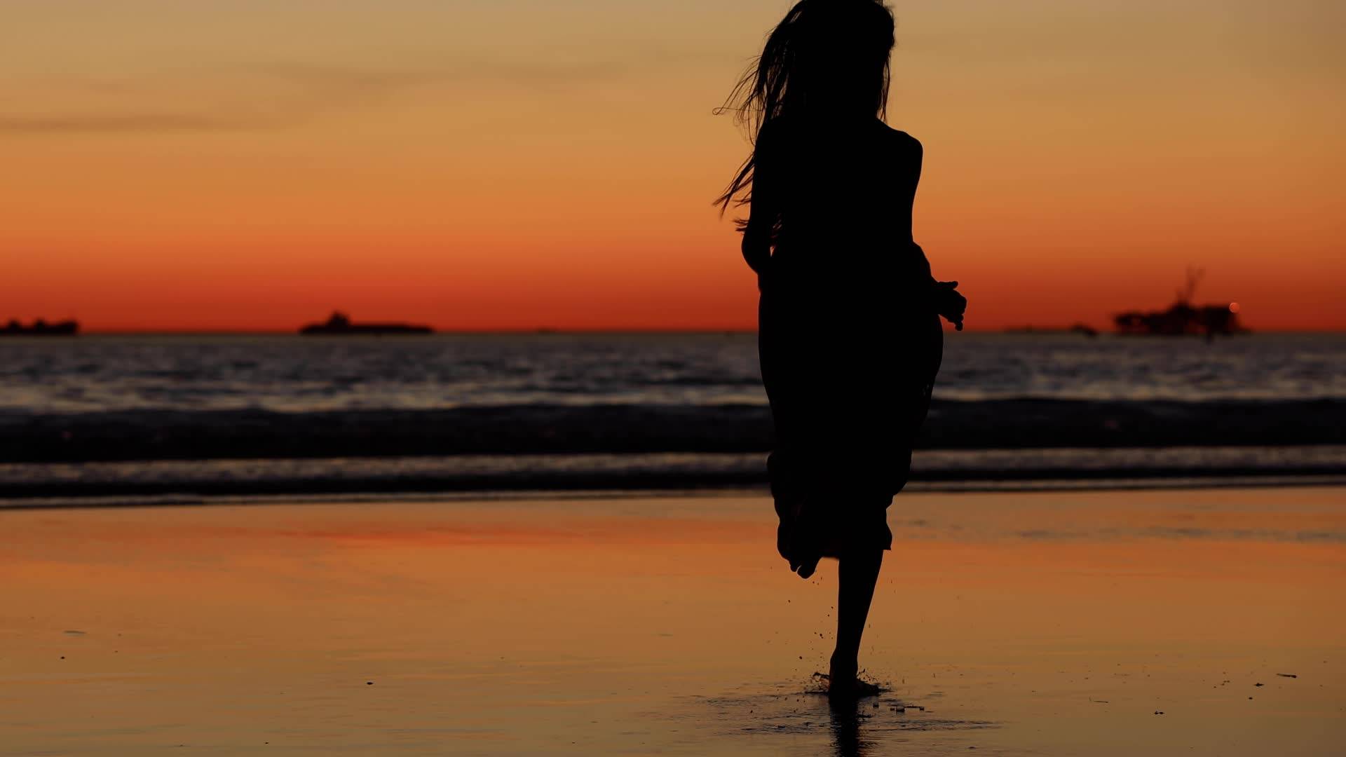 日落下海边女孩子在沙滩边跑步视频素材