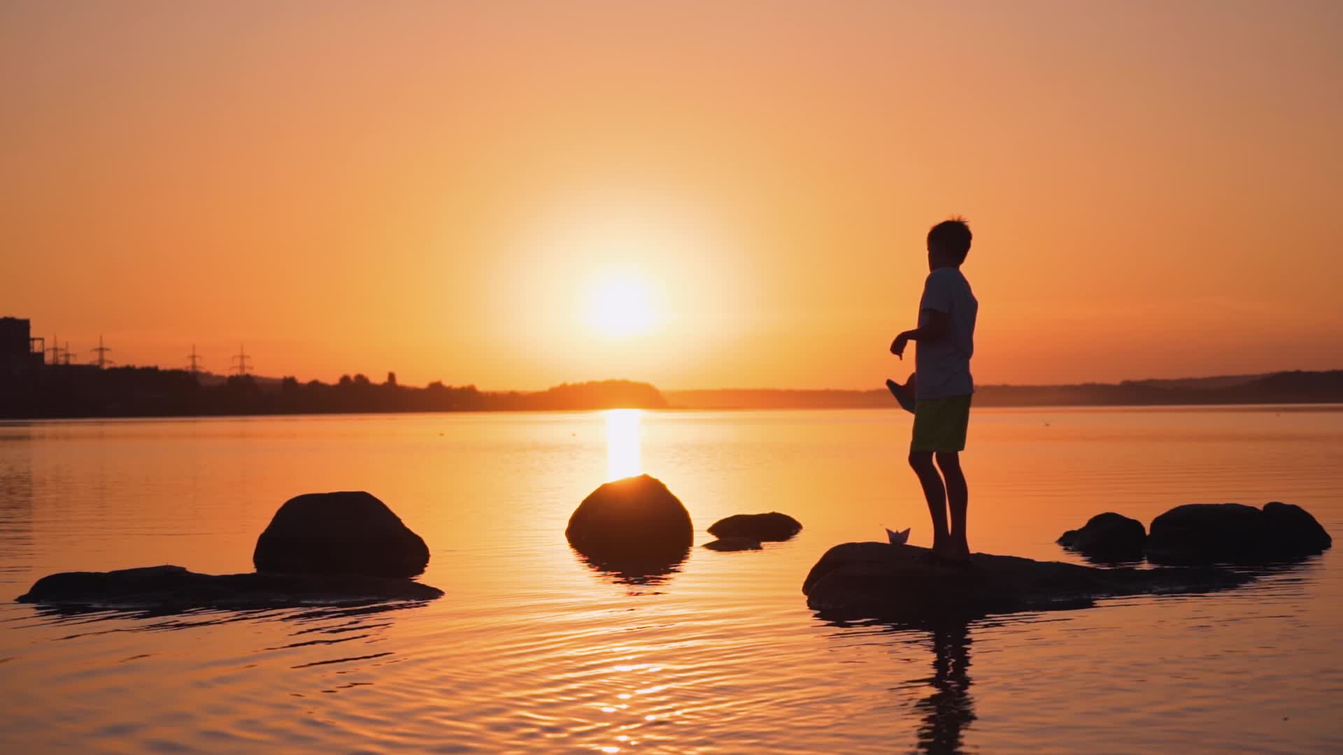 夕阳边的池塘边小男孩玩飞机视频素材