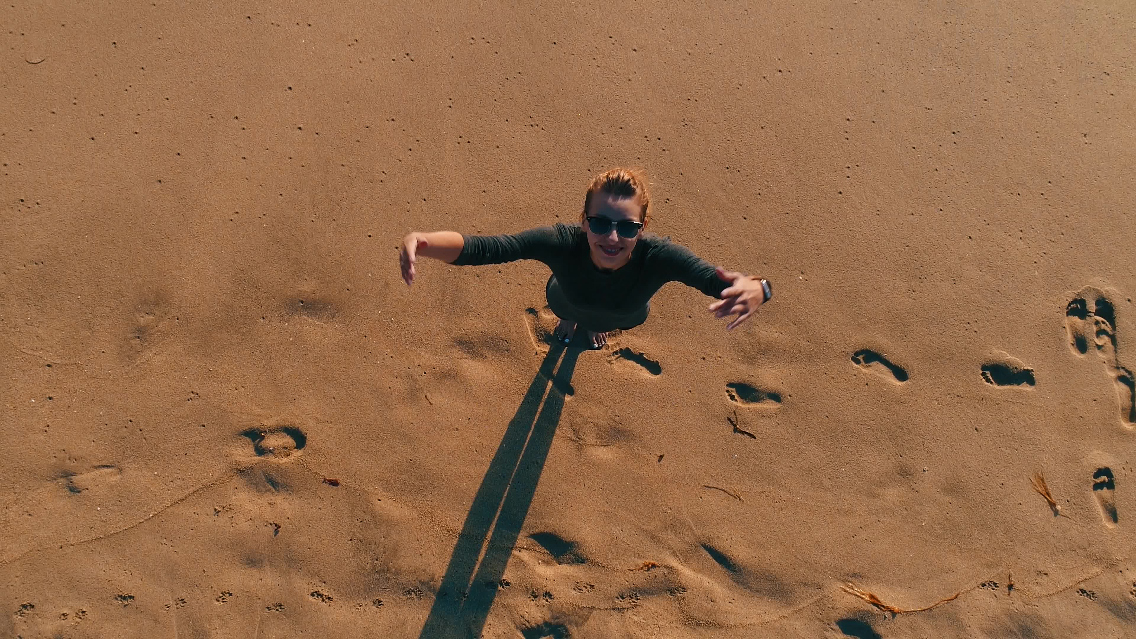 在海边沙滩上张开双手仰望天空