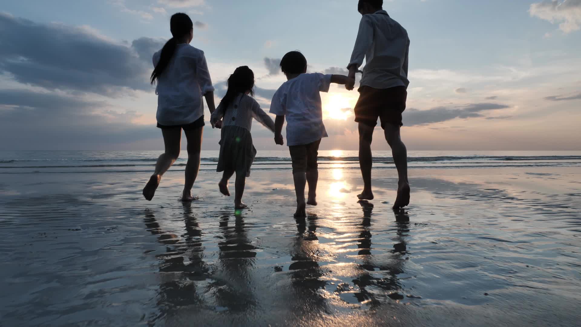 一家四口手牵手在夕阳下的海边奔跑视频素材