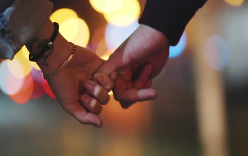 霓虹灯光中勾着小手指的情侣们