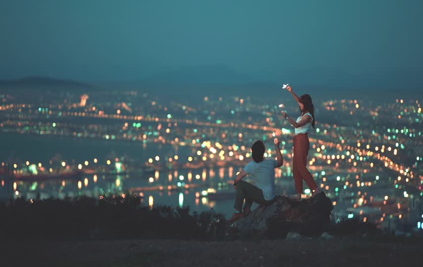 情侣在山顶游玩，山下灯火辉煌
