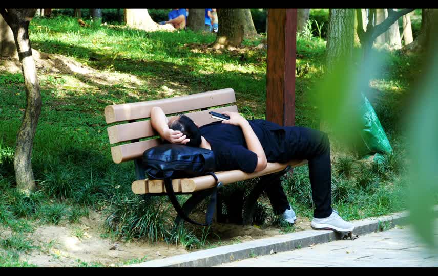 在公园长凳躺着午休的失业人员短视频素材